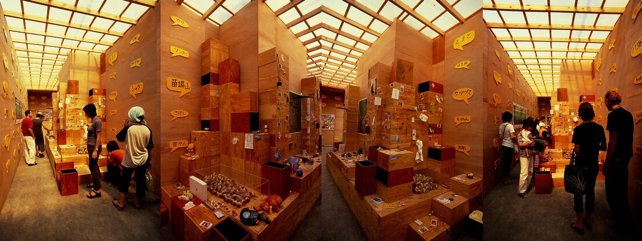 A panoramic view of an art installation featuring wooden structures and visitor interaction.